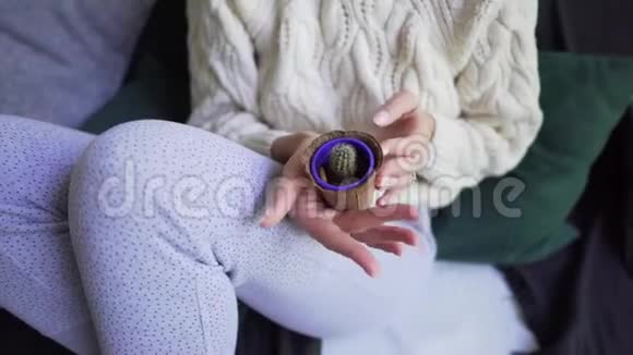 一个穿睡衣和白色毛衣的女人拿着一小壶自制的仙人掌Hygge或Lagom概念视频的预览图