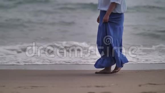 穿裙子的女人在风和日丽的天气里沿着海岸散步裙子在风中发展视频的预览图