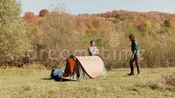 美丽的年轻夫妇互相帮助搭起了露营帐篷视频的预览图