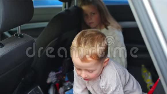 孩子们坐在汽车的后座上在等父母视频的预览图