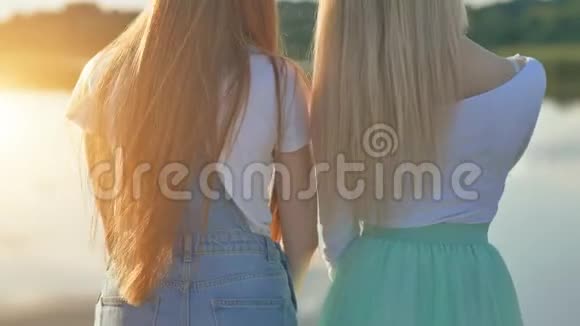 两个金发女孩站在温暖的阳光明媚的夜晚视频的预览图