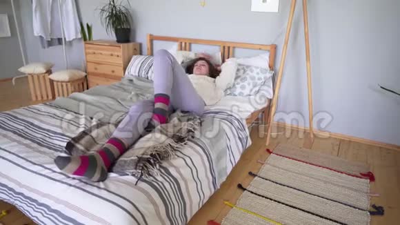 穿着家居服的漂亮女人在床上裹着羊毛毯睡着了视频的预览图