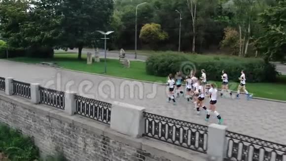 12名穿制服的年轻女子正在河边慢跑用空中射击视频的预览图