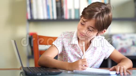 小女孩用笔记本电脑和笔记本做作业视频的预览图