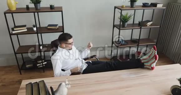在办公室里快乐的男人梦想家正坐在椅子上玩一把想象中的吉他视频的预览图