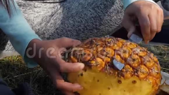 女人用菜刀在草地上削菠萝关闭POV视频的预览图