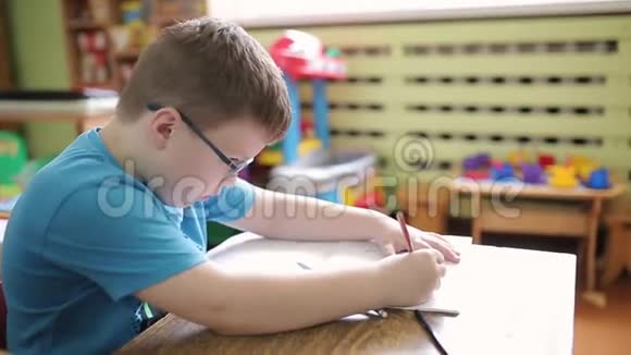 小学时一个戴眼镜的男孩用铅笔在笔记本上写字解决了逻辑和逻辑问题视频的预览图