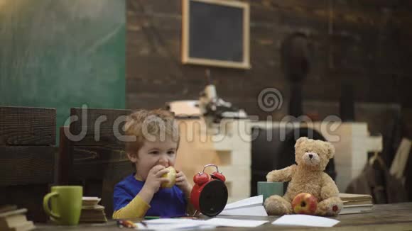 孩子吃多汁的苹果金发男孩在上课之间休息金发男孩在学校教室里休息吃苹果视频的预览图