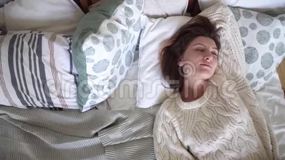 年轻漂亮的女人穿着白色毛衣躺在床上做梦上床睡觉视频的预览图