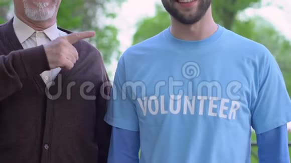 老人和社工指着印有志愿者标志的t恤视频的预览图