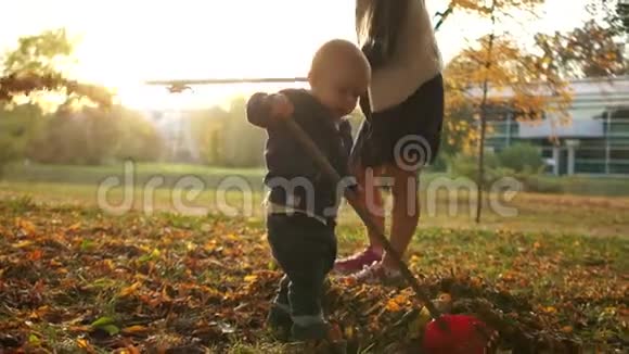 妈妈助理幼儿男孩帮姐姐收拾后院的落叶兄弟姐妹视频的预览图