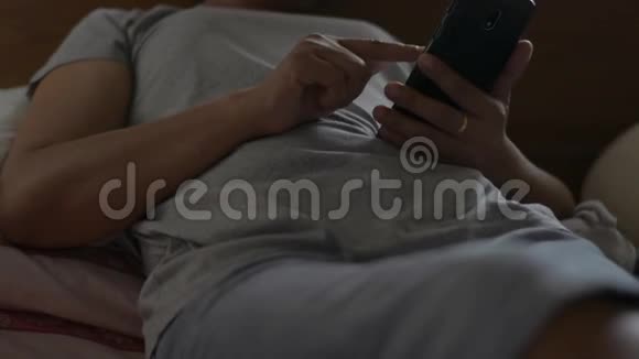 关闭女性手使用手机社交在线亚洲女人在床上用智能手机检查社交应用程序视频的预览图