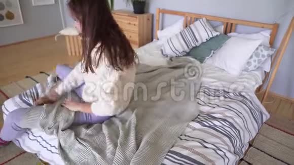 一个穿着家居服的女人下床用灰色格子铺床罗夫斯堪的纳维亚风格公寓视频的预览图