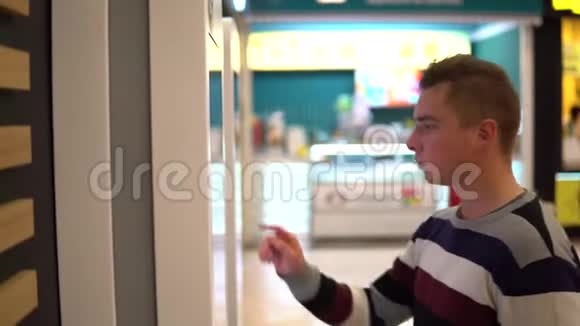 一个年轻人在购物中心的触摸终端点菜现代技术在食品法庭上不用等待视频的预览图