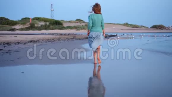 活跃的女人穿着裙子在海滩海岸线上奔跑视频的预览图