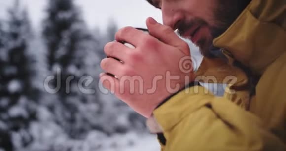 在森林中央的严冬里他喝了一些热茶来获得冰冻的红手的魅力旅游画像视频的预览图