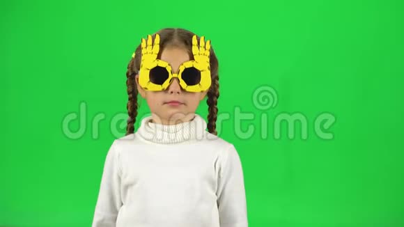 戴着滑稽眼镜的可爱女孩在绿色屏幕上摇着头视频的预览图