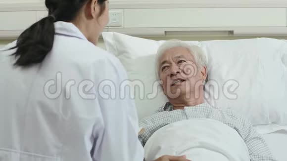 年轻的亚洲女医生与医院病房的老年男性病人交谈视频的预览图