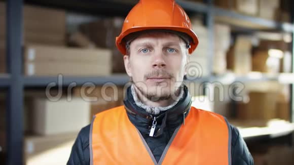 与面包和胡子工人一起工作戴着头盔和工作服站在架子旁边把头盔固定在照相机上视频的预览图
