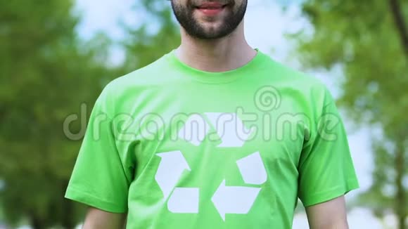 微笑的男性环保活动家指着t恤上的回收符号打印视频的预览图