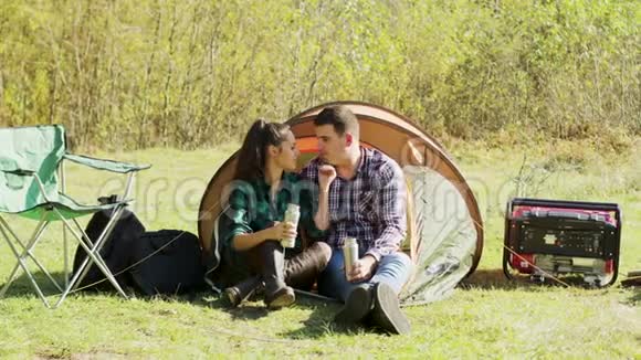 男朋友坐在露营帐篷前亲吻女友的脸颊视频的预览图
