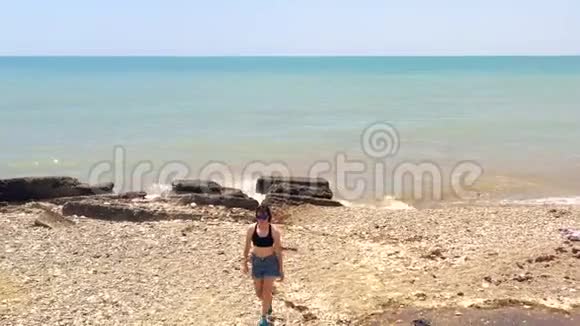 穿着蓝色短裤和黑色太阳镜离开海滩的女孩视频的预览图