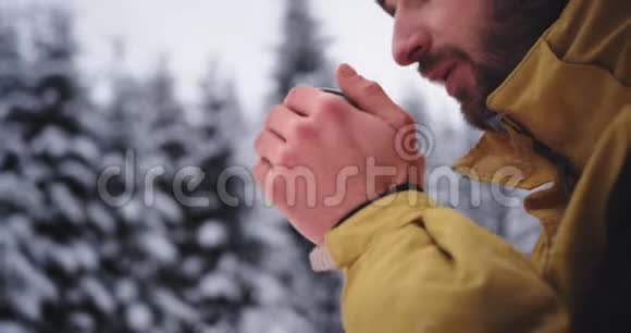 一个年轻的旅游女巫在大雪林中的严冬里被冻僵了他喝了一些热辣的饮料视频的预览图