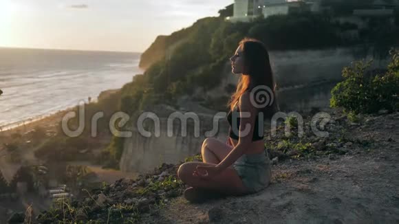 迷人的年轻女孩做瑜伽冥想日落海岸概念慢运动日落时分约吉人祈祷视频的预览图