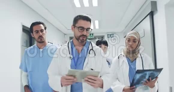 一队医生在医院走廊散步讨论x光和病人记录视频的预览图