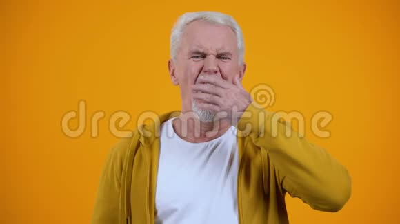 昏睡的老人在橙色背景下相机上打哈欠失眠问题视频的预览图