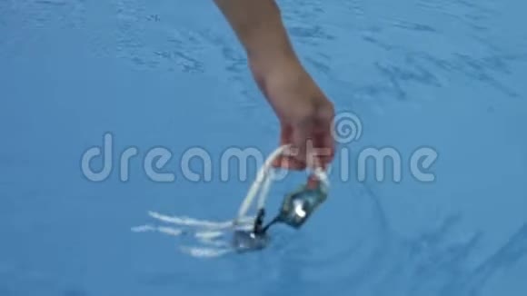 一个女人手在蓝色清澈的水中浸泡游泳眼镜视频的预览图