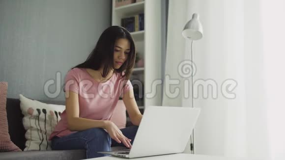 年轻女子看手提电脑屏幕和书写视频的预览图