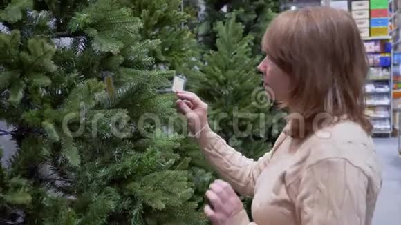 成熟的白种人女人在购物中心选择人造圣诞树视频的预览图