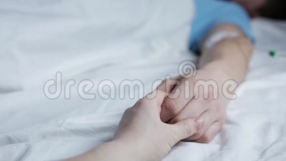 躺在病床上睡觉的男人手女人握着他的手视频的预览图
