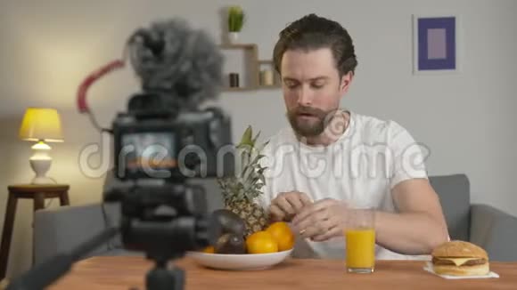 一个年轻人一个博客写了一段视频他坐在镜头前的桌子旁谈论水果和水果视频的预览图