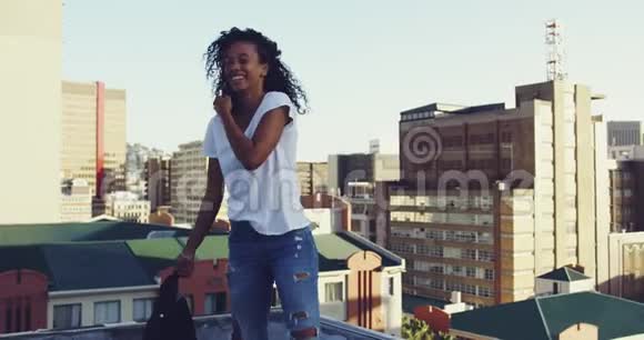 城市屋顶上时髦的年轻女子挥舞着夹克视频的预览图