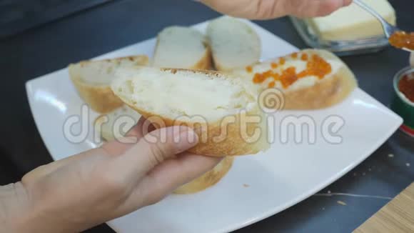女人用勺子把红鱼子酱放在面包上夹上黄油和鱼子酱的三明治家庭烹饪女人播红鱼子酱视频的预览图