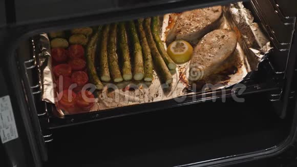 从烤箱里准备晚餐的女人电烤箱中的煮熟的鱼和蔬菜家庭厨房烤三文鱼牛排厨师视频的预览图