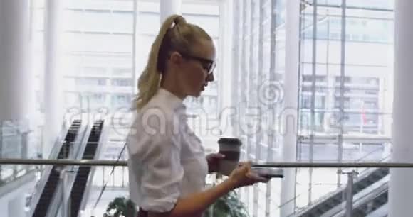 白种人女商人在办公室大堂使用手机和喝咖啡的侧景4视频的预览图