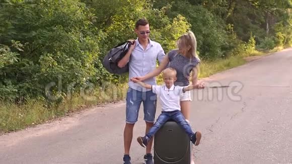 一个幸福的家庭和一个年轻的儿子在树林里带着手提箱的路上的肖像视频的预览图