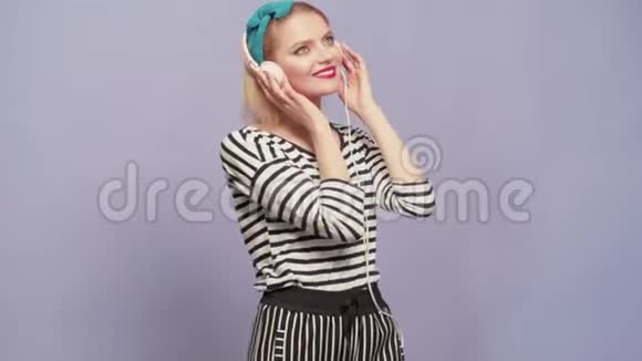 老式管家女人用耳机听音乐复古把女女家庭主妇穿着五颜六色的上衣视频的预览图