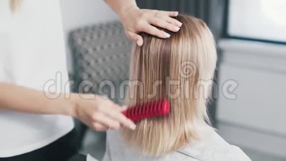 在头发护理程序前应将发型师的双手合拢梳理女性湿发视频的预览图