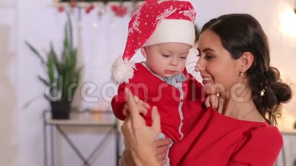 一位母亲抱着一个戴着圣诞帽的小孩子的特写镜头圣诞节视频的预览图