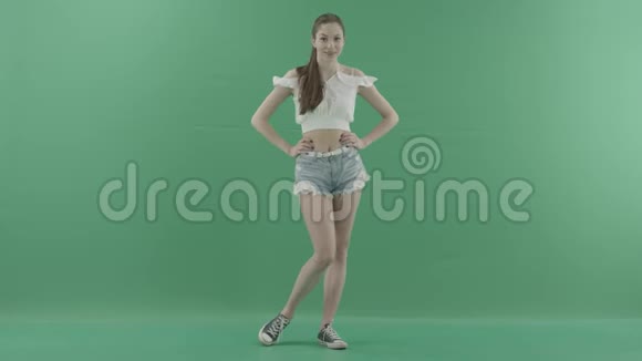 漂亮的年轻逗趣女人站在绿色的背景下双手叉腰视频的预览图