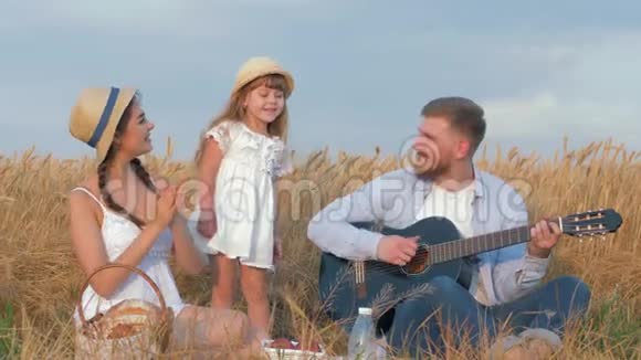 欢乐的家庭郊游爸爸演奏弦乐器妈妈拍手小女儿跳舞视频的预览图