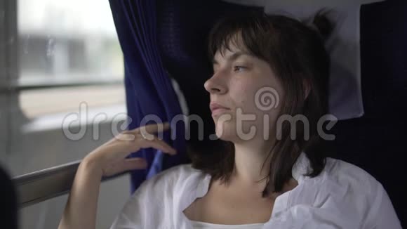 忧郁的女人带着悲伤的表情在火车上旅行视频的预览图