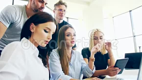 一家年轻人聚会并观看平板电脑上的信息的公司视频的预览图