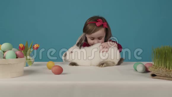 快乐的小女孩和兔子玩她给兔子一个复活节彩蛋复活节快乐视频的预览图