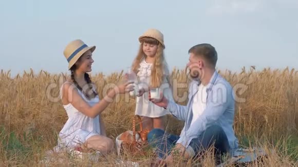 家庭草地野餐小女孩把牛奶倒进她父母的眼镜他们交流喝牛奶一边喝牛奶视频的预览图