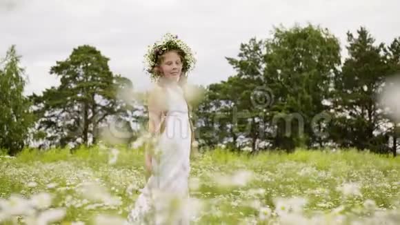 头上戴着雏菊花圈的少女正走在鲜花盛开的草地上视频的预览图